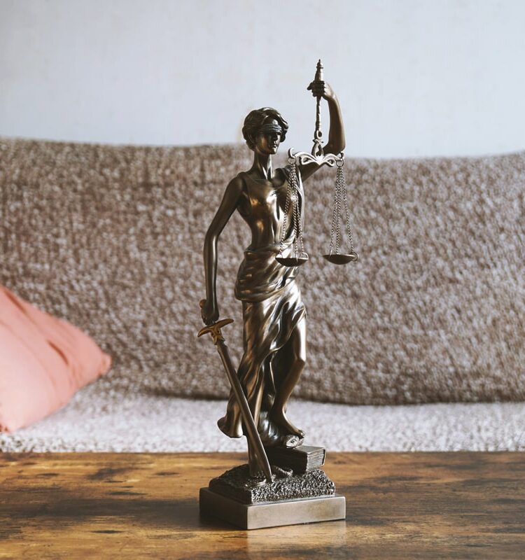 Das Bild zeigt eine Justitia-Statue auf einem Tisch, der im Wohnzimmer steht und dient als Beitragsbild der Seite zum Miet- und Wohneigentumsrecht.